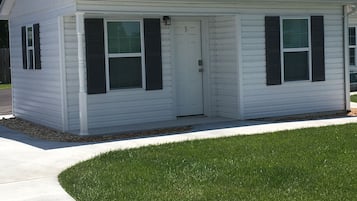 A small, single-story house with a white exterior, dark shutters, and a number '3' on the door.