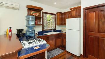 A compact kitchen with wooden cabinets, a white refrigerator, a gas stove, and a water dispenser.