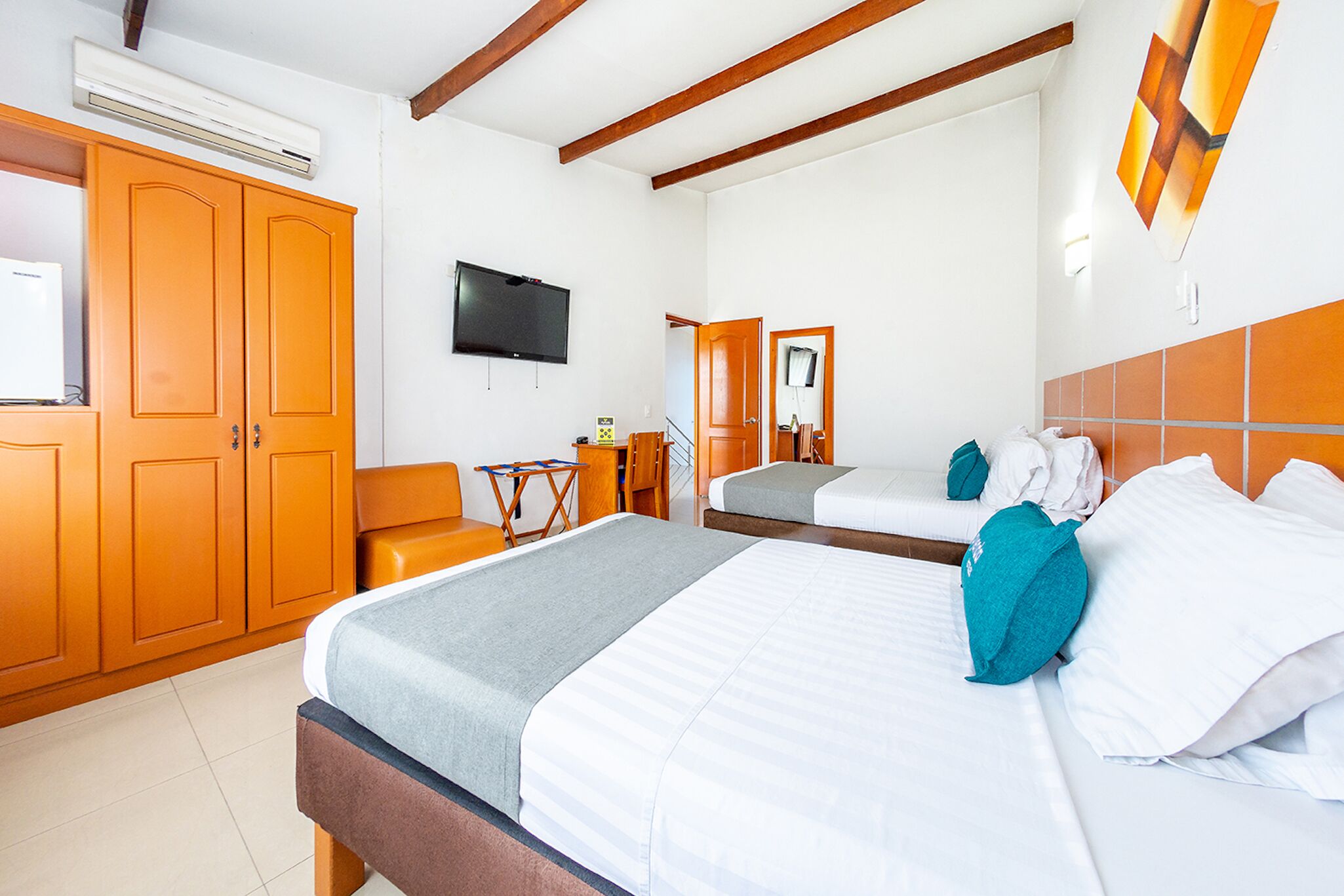 A hotel room with a large bed, a smaller bed, a TV, and a wardrobe.