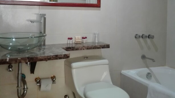 A bathroom with a glass bowl sink, a toilet, a bathtub, and a shower. - Inka Tower (Machu Picchu)