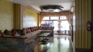 A lobby with a stone bench, a sofa with cushions, a coffee table, and a fire extinguisher. - Inka Tower (Machu Picchu)