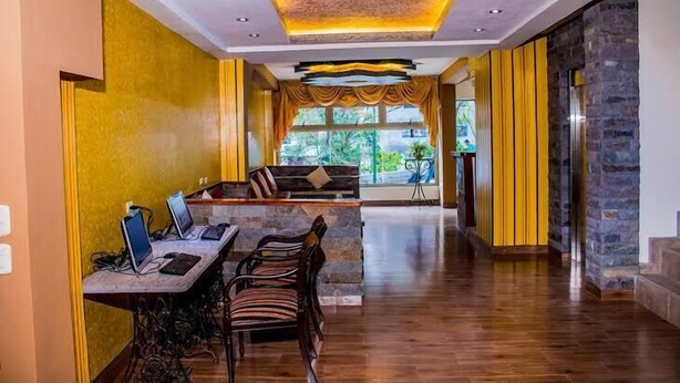 A modern hotel lobby with a long reception desk, comfortable seating, and a view of greenery outside. - Inka Tower (Machu Picchu)