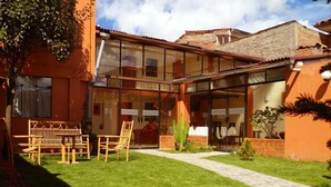 Un edifici amb façana de vidre, seients a l'exterior i un jardí ben cuidat.