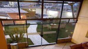 Habitació amb una gran porta de vidre que dona a un pati interior, un safataire i un sofà de pell.