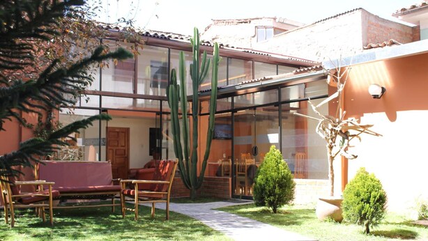 Zona de pati amb tancament de vidre, un cactus i un arbre petit.