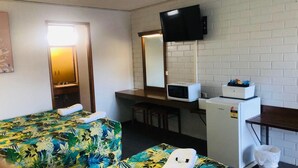 Habitación de hotel con cama, escritorio, microondas, refrigerador y televisor.