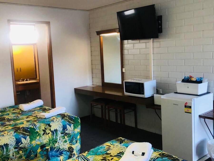 Una camera d'albergo con un letto, una scrivania, un forno a microonde, un frigorifero e una televisione.