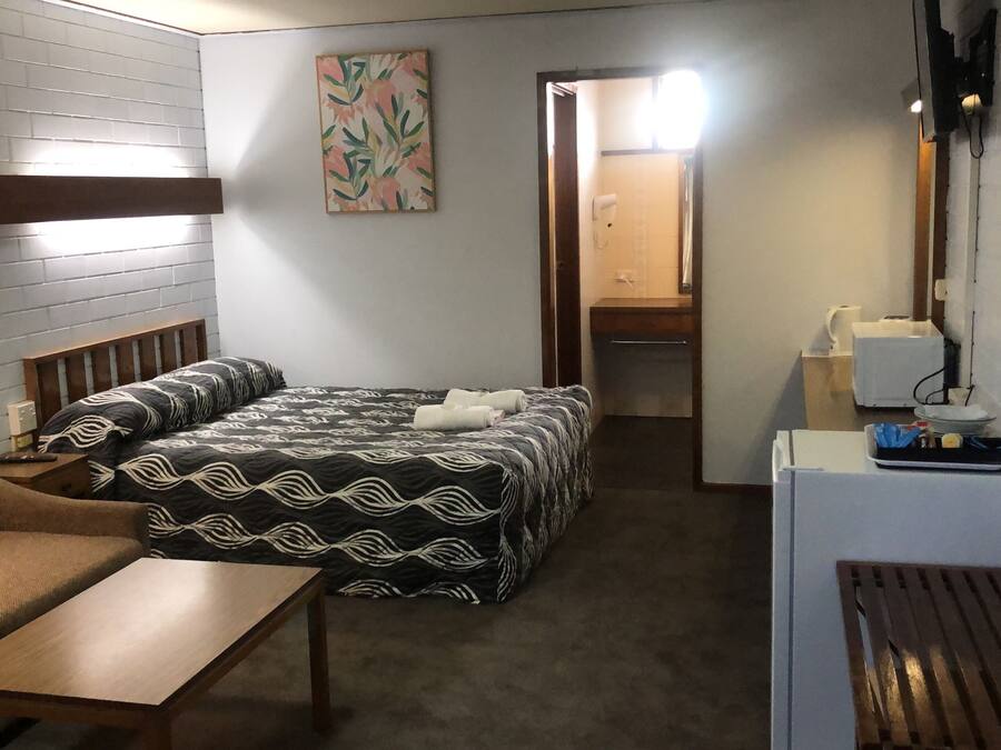 A hotel room with a bed, a sofa, a small table, a desk, and a mirror.