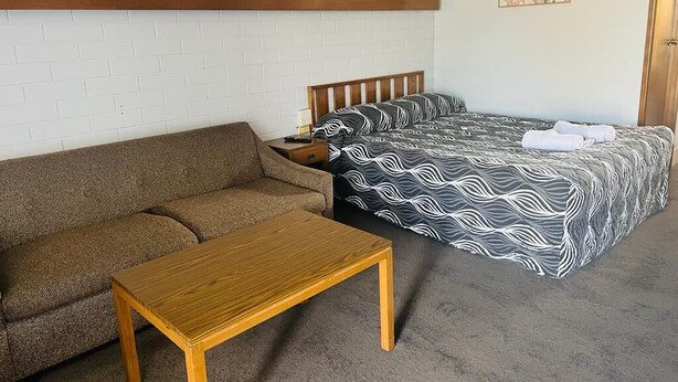Una habitación con una cama, un sofá y una mesa de madera.