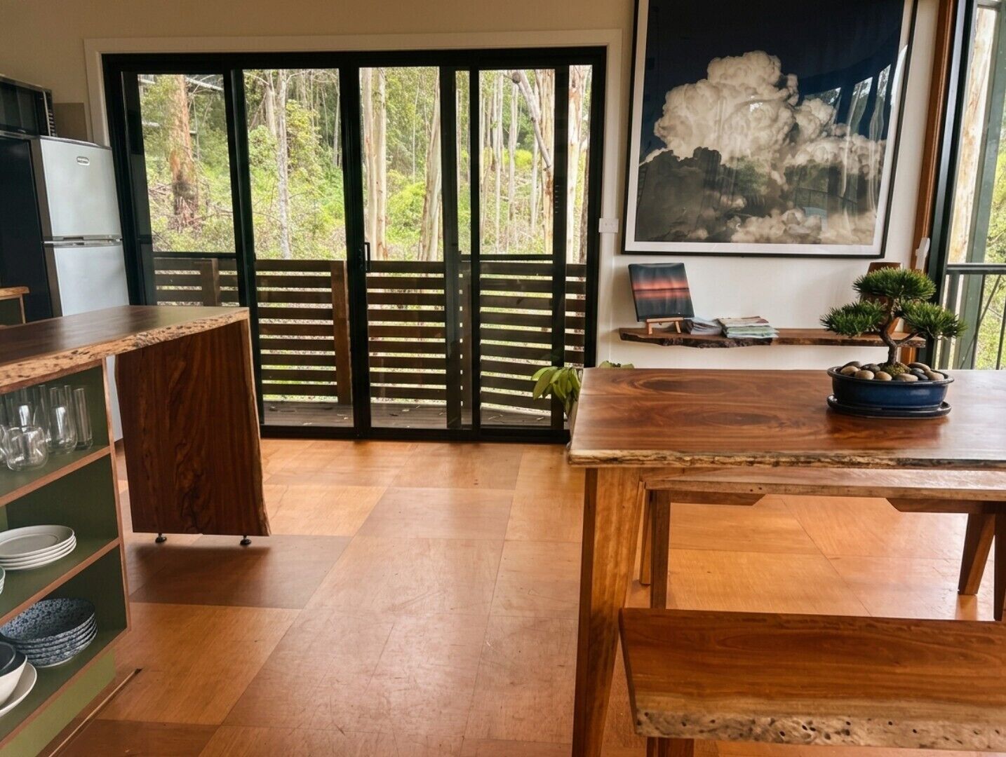 Cocina moderna con encimera de madera, una mesa de comedor y vistas a un jardín mediante grandes puertas correderas.