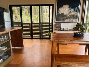Cocina moderna con encimera de madera, una mesa de comedor y vistas a un jardín mediante grandes puertas correderas.