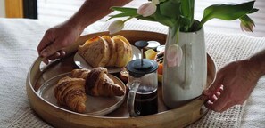 A tray with croissants, a coffee pot, and a vase with flowers.