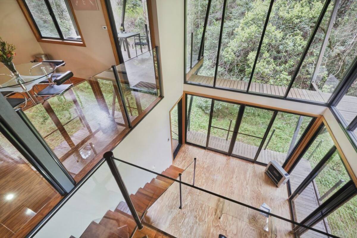 A multi-level interior with glass railings, wooden flooring, and a view of the outdoors.