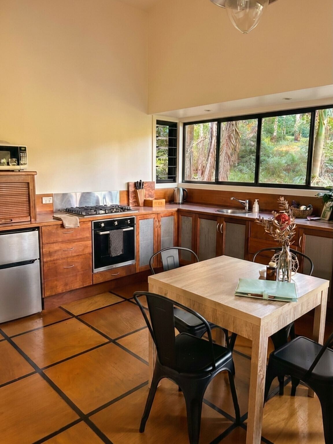 A kitchen with a dining area, a refrigerator, a stove, and a window with a view of greenery.
