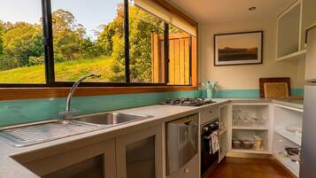A kitchen with a large window, a sink, cabinets, and a stove.