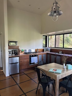 Una cocina moderna con comedor, electrodomésticos de acero inoxidable y ventanas amplias.