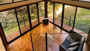 A modern interior with large windows, a wooden floor, and a black sofa.