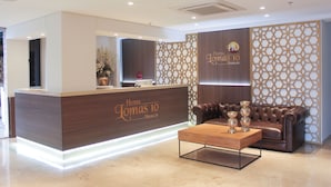 A modern hotel reception area with a wooden reception desk, a leather sofa, and a coffee table. - Hotel Lomas 10 (Medellín)