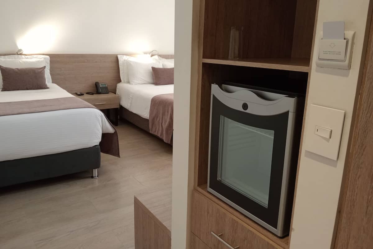 Habitación de hotel con cama, mesitas de noche, armario y televisión integrada.