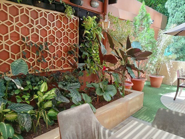 A garden area with various potted plants, a wooden lattice fence, and outdoor furniture.