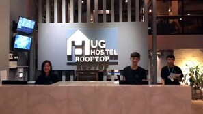 Welcome to Hug Hostel Rooftop, where a modern reception area awaits with a flat-screen TV and comfortable space for travelers.