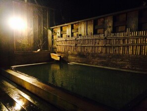 A dimly lit indoor swimming pool with a wooden fence and steps leading into the water.