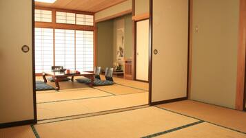 A traditional Japanese room with tatami flooring, sliding doors, and a low table with cushions.