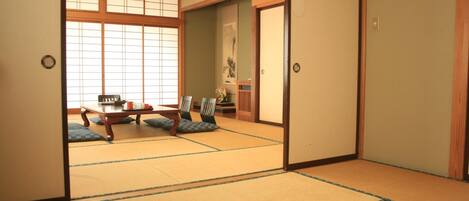 A traditional Japanese room with tatami flooring, sliding doors, and a low table with cushions.