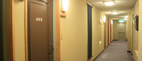 A hotel hallway with doors numbered 402 and 403, fluorescent lighting, and a carpeted floor.