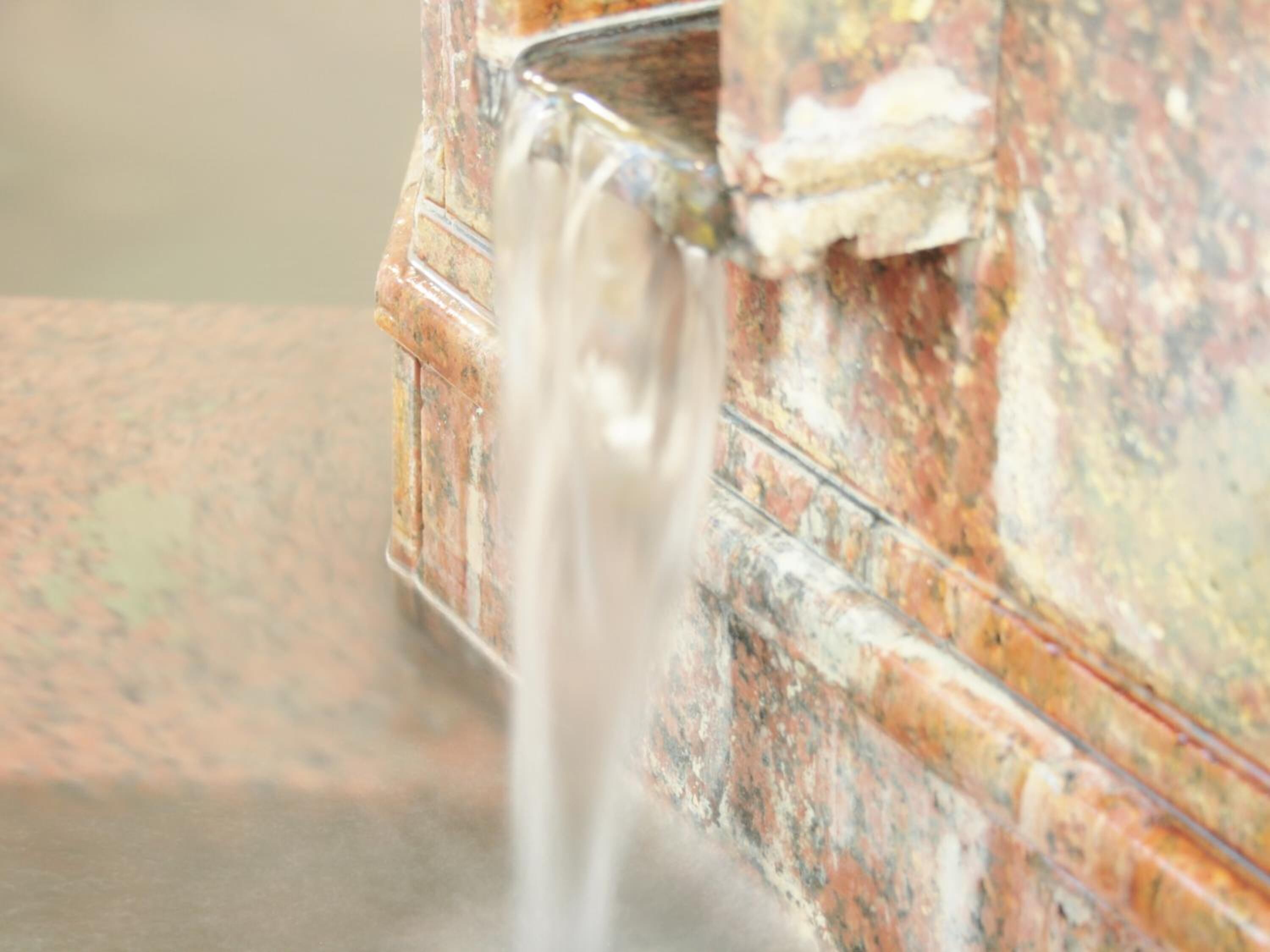 A close-up of a faucet with water flowing from it.