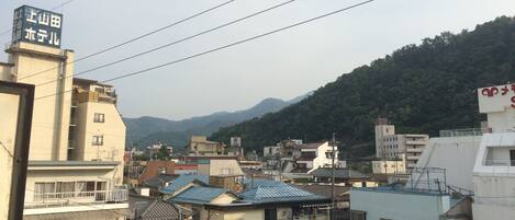 A residential area with multi-story buildings, some with balconies, and a mountainous backdrop.