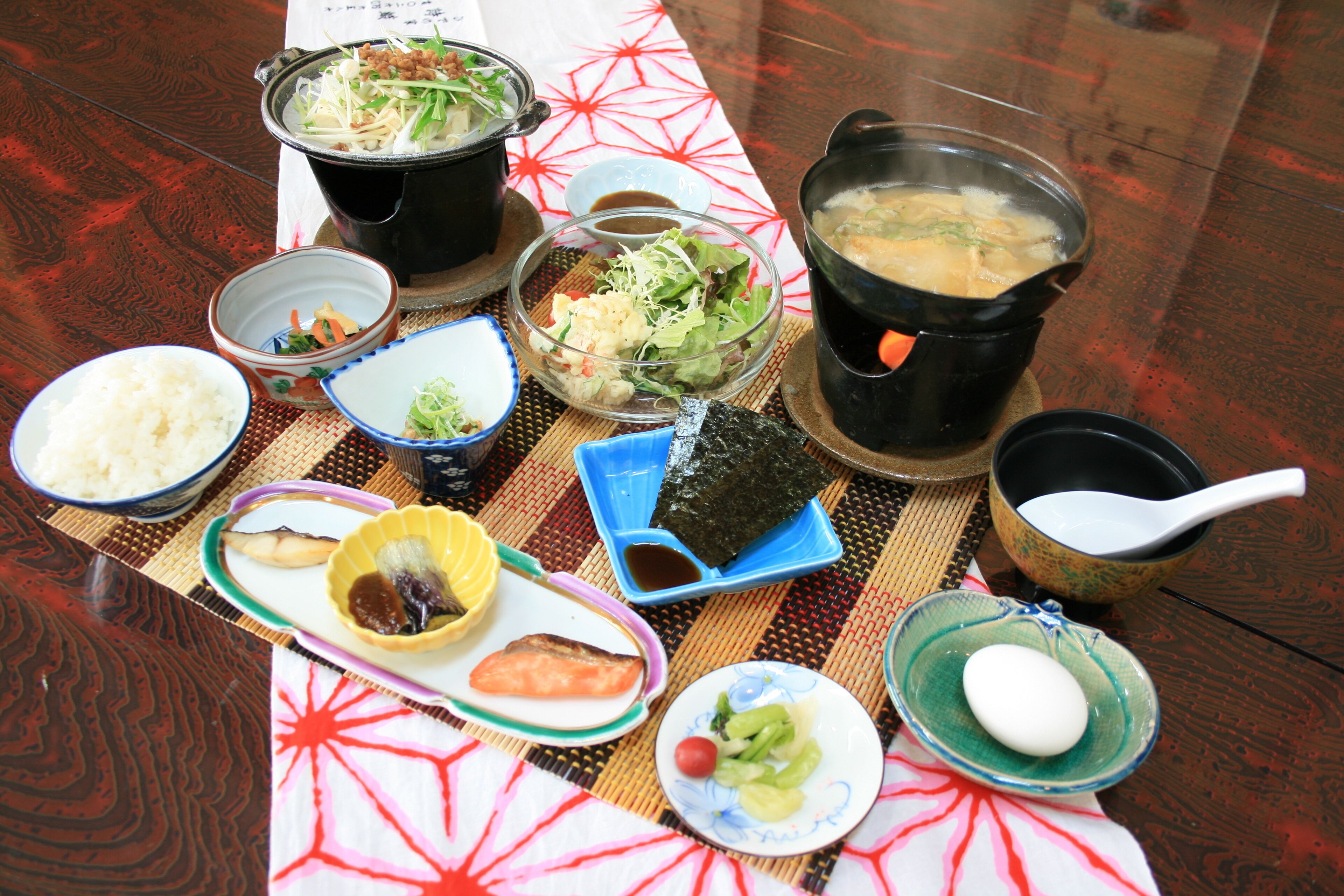 A table with various dishes including rice, soup, and vegetables, suggesting a meal setting.