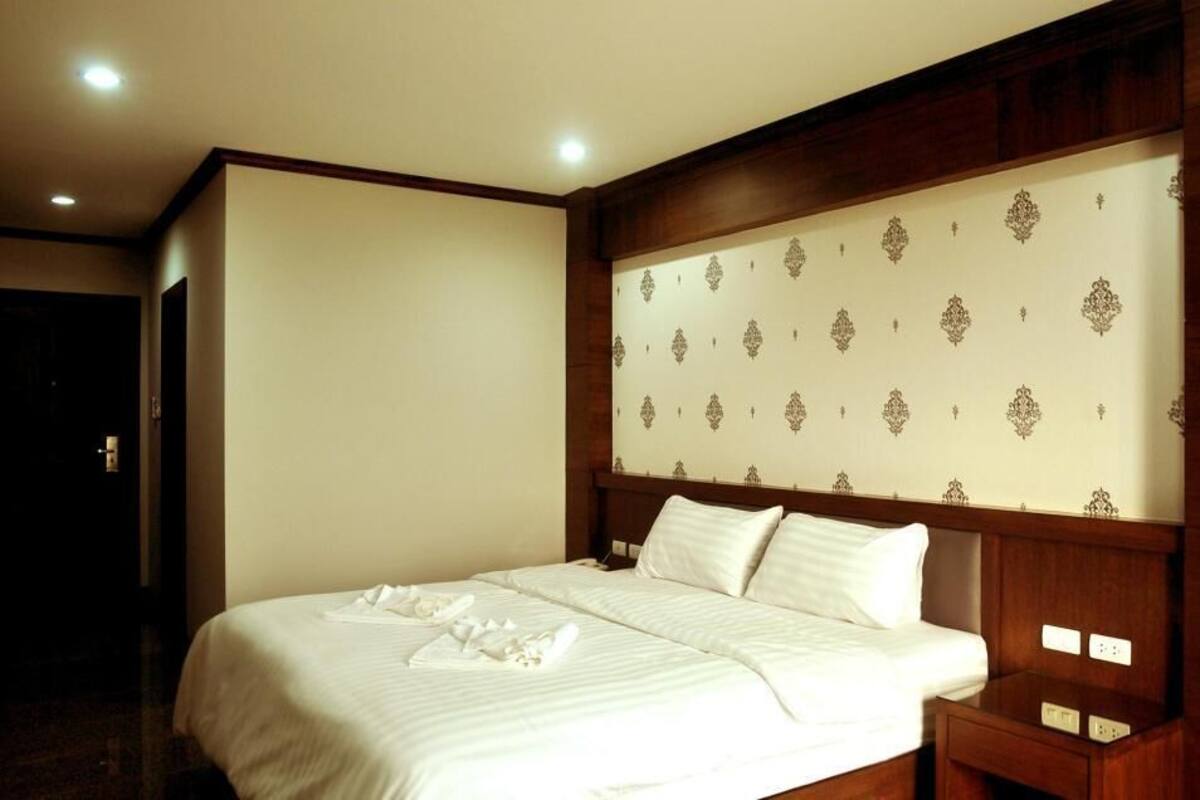 Una habitación de hotel con una cama grande, cabecera de madera y una mesita de noche.