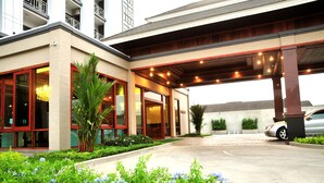 L’entrée d’un hôtel, avec une allée couverte, de grandes fenêtres et un espace de stationnement.