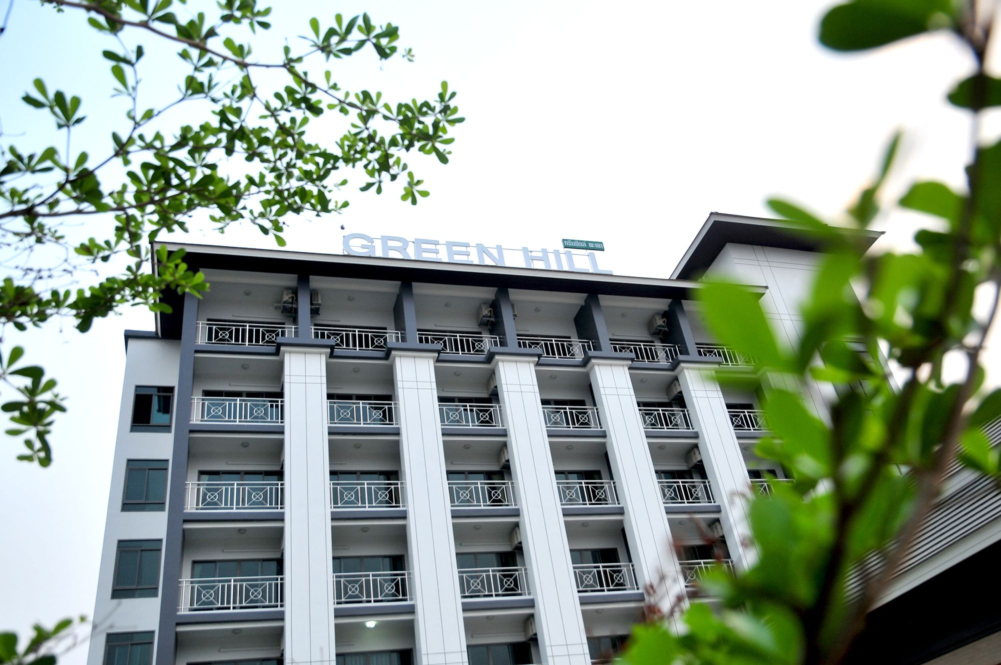 Un edificio de varios pisos con un letrero que dice "GREEN HILL".