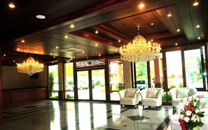 Un vestíbulo amplio con candelabros, ventanas grandes y una zona de recepción.