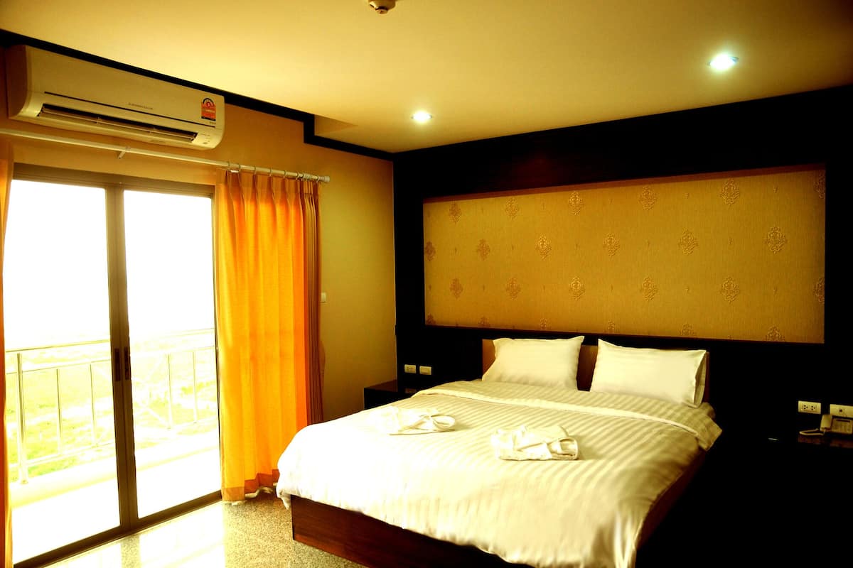 Habitación de hotel con cama, aire acondicionado, ventana con cortinas y vista al exterior.