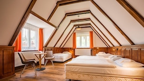 Ein gemütliches Schlafzimmer im Dachgeschoss mit einem großen Bett, einem Schreibtisch und zwei Stühlen.