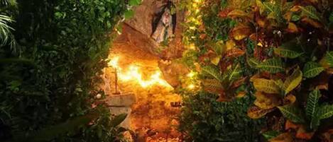 A lush indoor garden with a rock formation, a small waterfall, and various plants.