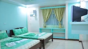 A room with two beds, a television on a stand, and a window with curtains. - Apartelle de Francesca (Puerto Galera)