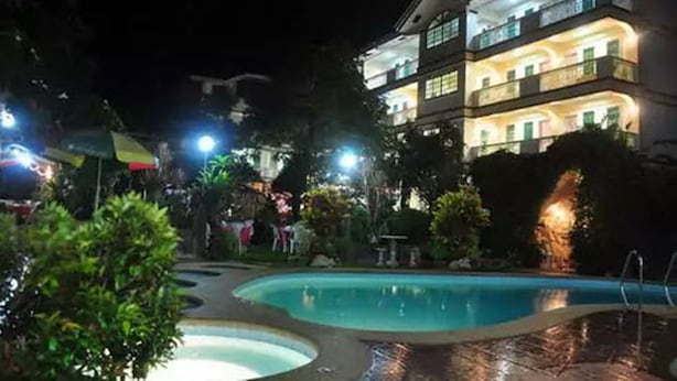 A multi-story hotel with a swimming pool and outdoor lighting. - Apartelle de Francesca (Puerto Galera)