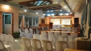 A conference room with rows of chairs, a podium, and a large screen. - Apartelle de Francesca (Puerto Galera)
