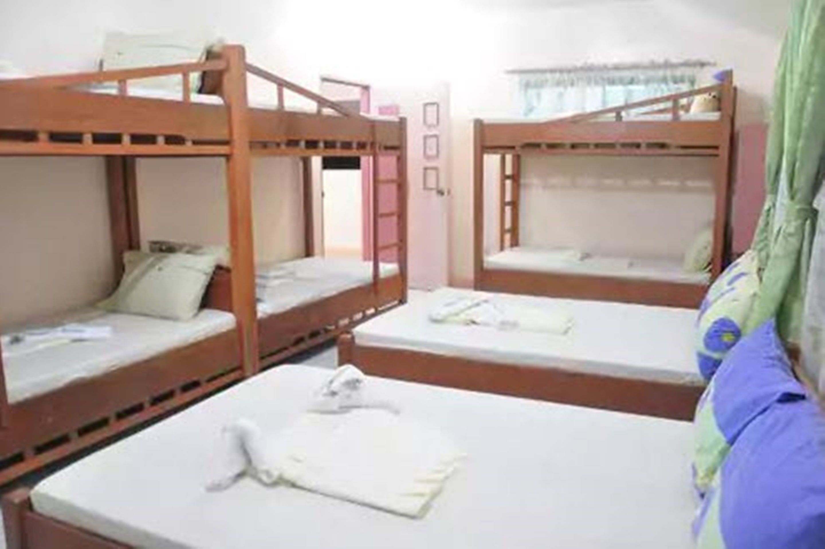 A room with three bunk beds, a door, and a window with curtains.