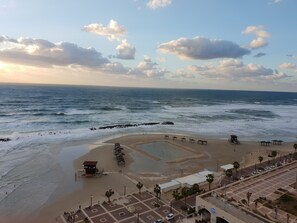 A beach with a lifeguard tower, umbrellas, and a parking area.