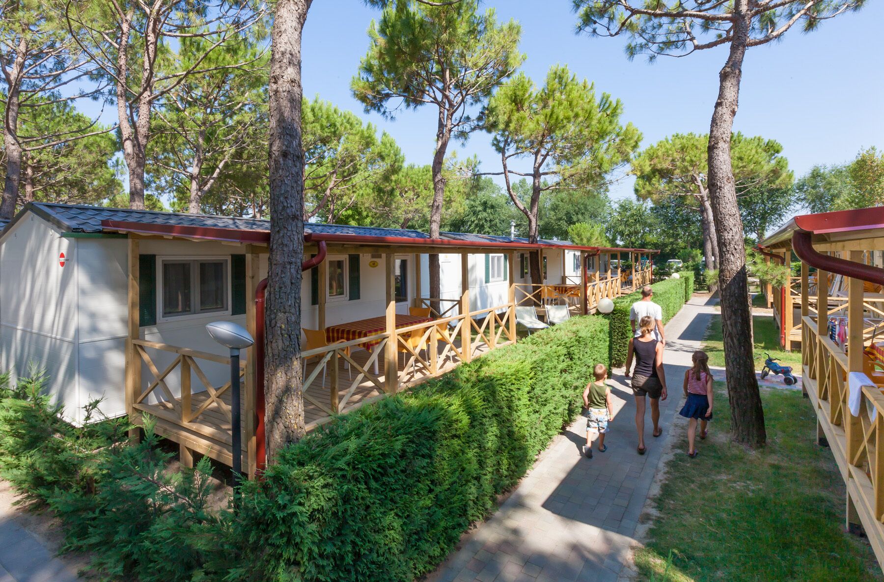 Une rangée de cabanes dotées de terrasses en bois et d’un chemin piétonnier dallé.