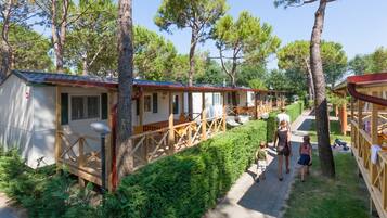 Une rangée de cabanes dotées de terrasses en bois et d’un chemin piétonnier dallé.