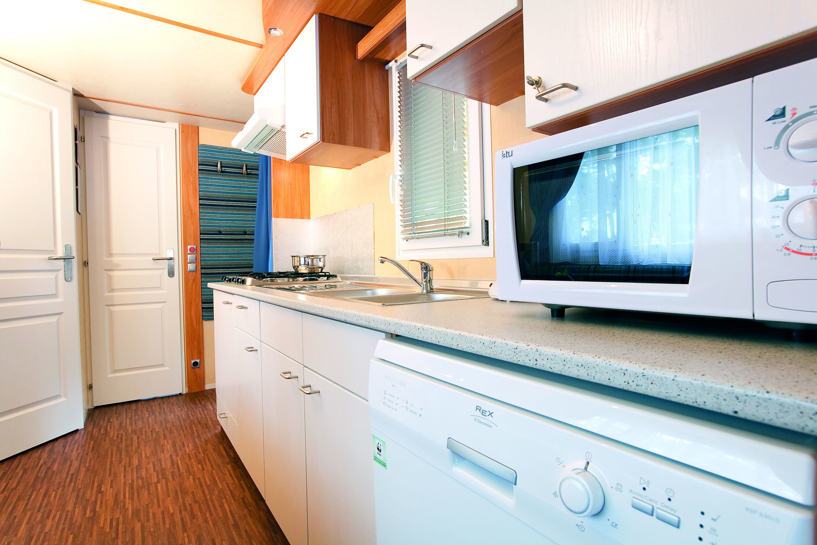 Una cocina compacta equipada con microondas, lavavajillas y un lavamanos.