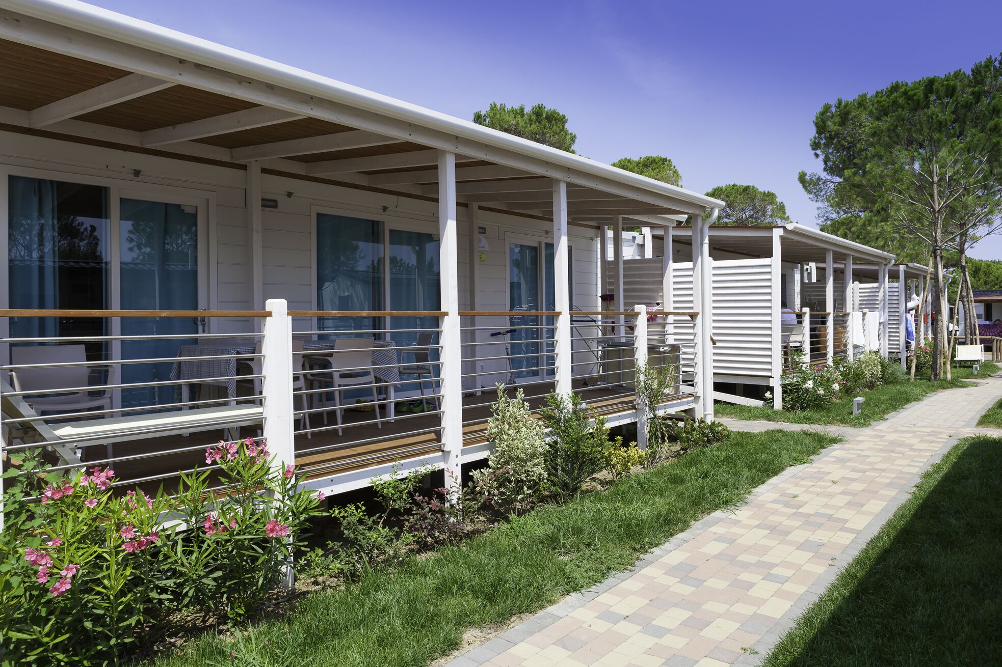 Une rangée de maisons mobiles, chacune dotée d’une véranda attenante, avec une petite table et des chaises.