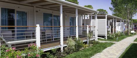 Une rangée de maisons mobiles, chacune dotée d’une véranda attenante, avec une petite table et des chaises.