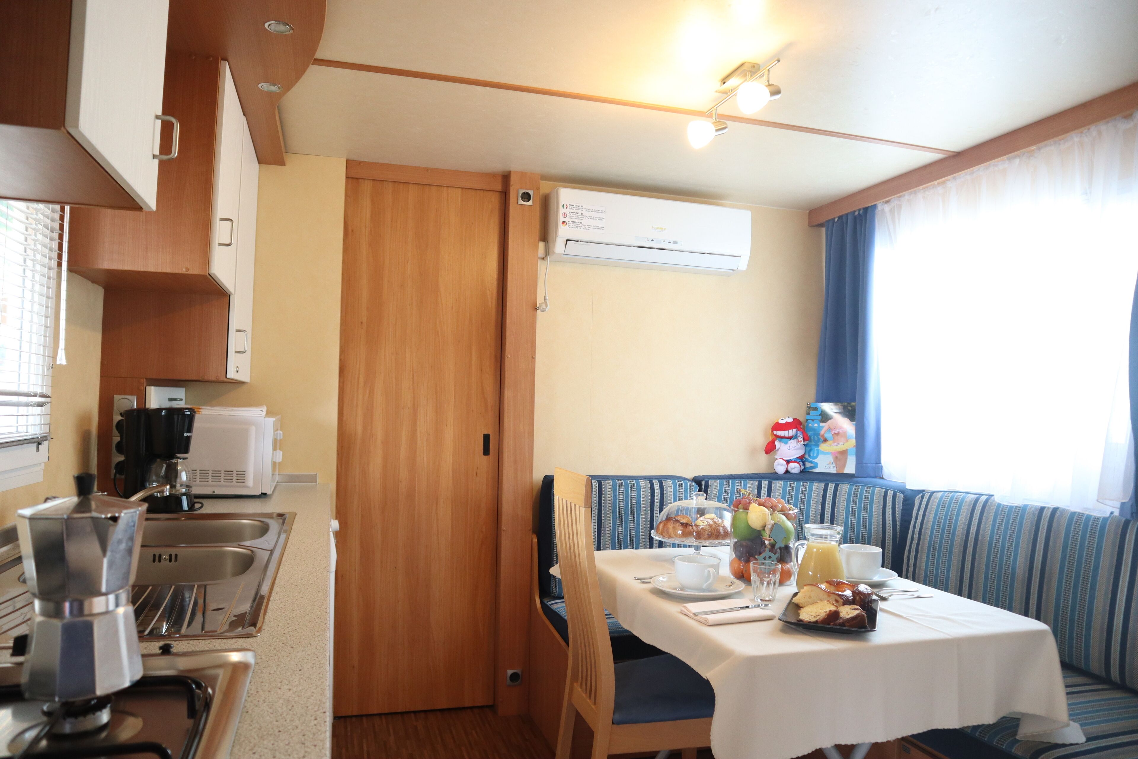 A compact kitchen with a coffee maker, sink, and a dining area with a table set for breakfast.